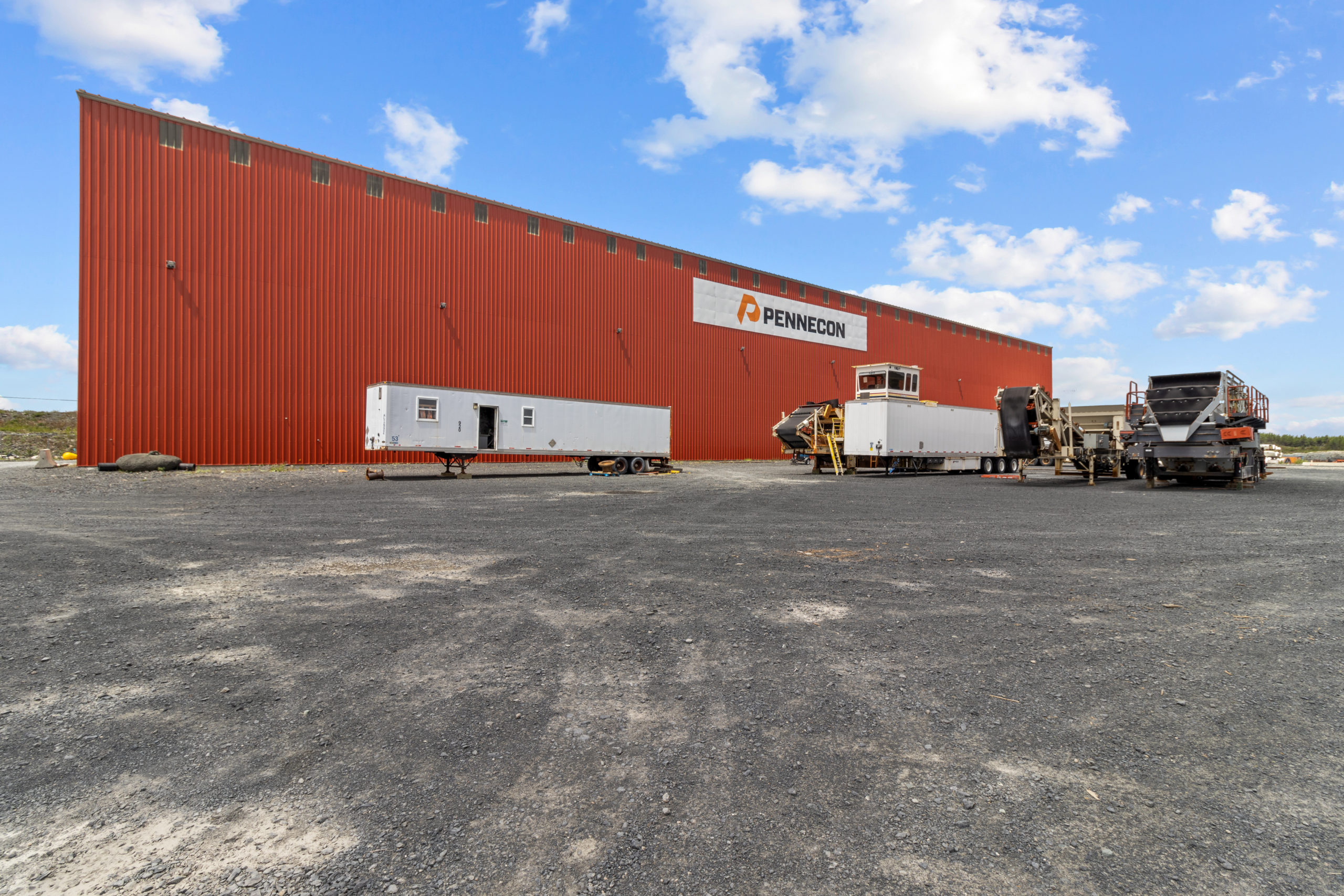 Side view of large warehouse with trailer and yard